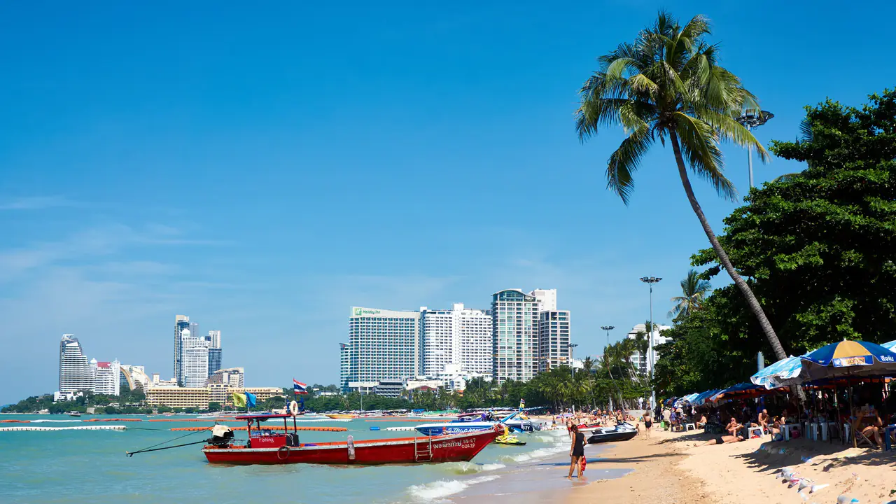 หาดพัทยายามเที่ยง เรือประมง ต้นมะพร้าว และตึกสูงเรียงรายตามแนวอ่าว